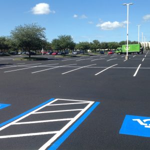 Worker applying black sealcoat to a large commercial asphalt surface Worker applying black sealcoat to a large commercial asphalt surface